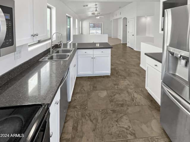 kitchen featuring dark stone countertops, sink, black appliances, pendant lighting, and white cabinetry