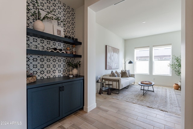 interior space with blue cabinetry, light hardwood / wood-style floors, and decorative backsplash