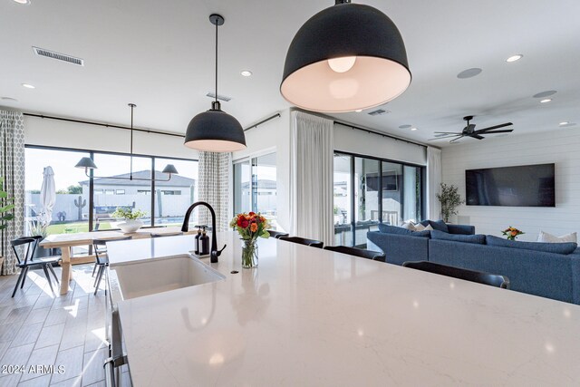 kitchen with ceiling fan, decorative light fixtures, sink, and light hardwood / wood-style flooring