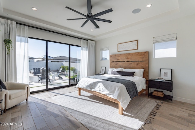 bedroom featuring multiple windows, ceiling fan, light hardwood / wood-style flooring, and access to exterior