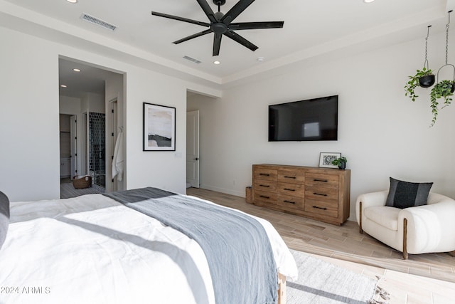 bedroom featuring ceiling fan, light hardwood / wood-style flooring, and ensuite bath