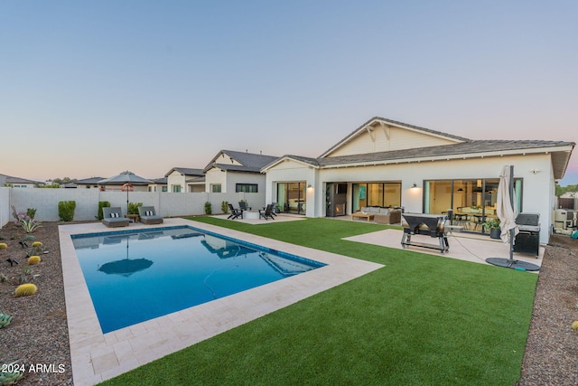 pool at dusk with an outdoor hangout area, a yard, and a patio