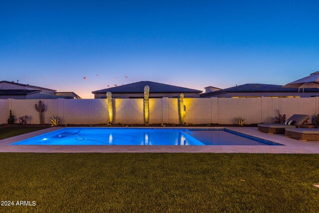 pool at dusk featuring a lawn and a patio area