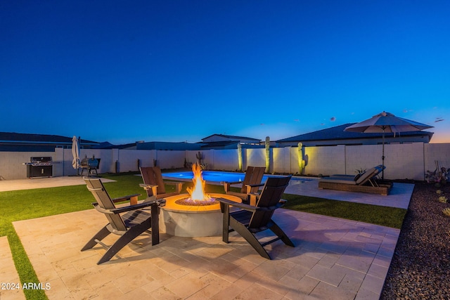 patio terrace at dusk with grilling area and an outdoor fire pit