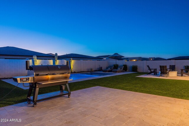 patio terrace at dusk featuring area for grilling and a yard