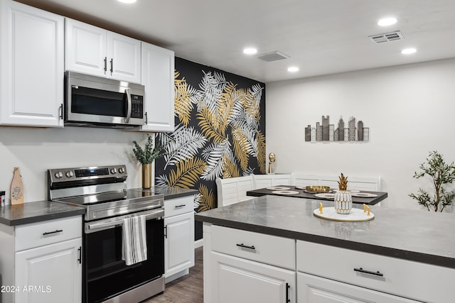 3814 N 36th St, Phoenix, AZ 85018 - kitchen with appliances with stainless steel finishes, dark countertops, recessed lighting, dark wood-style flooring, and white cabinetry