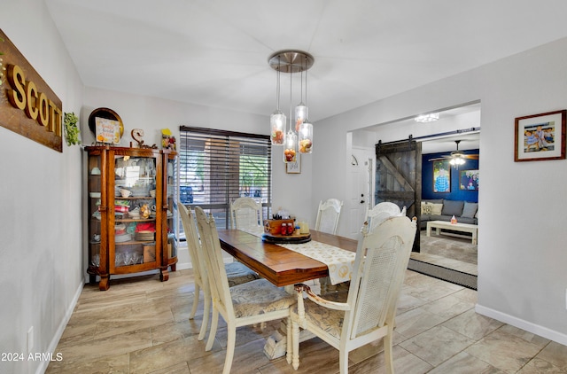 dining space with a barn door and ceiling fan