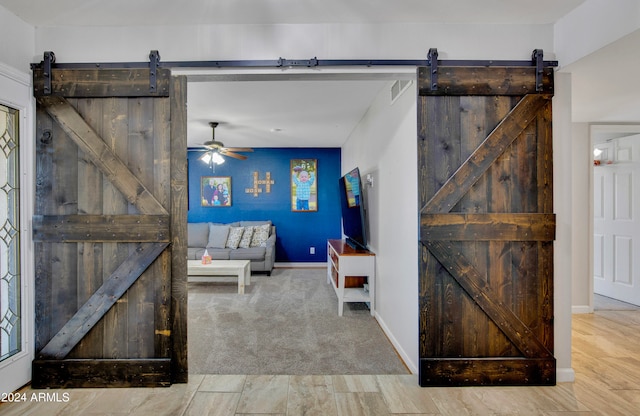 interior space featuring a barn door, carpet floors, and ceiling fan