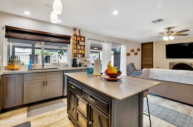 kitchen featuring a kitchen island, sink, a breakfast bar, a fireplace, and ceiling fan