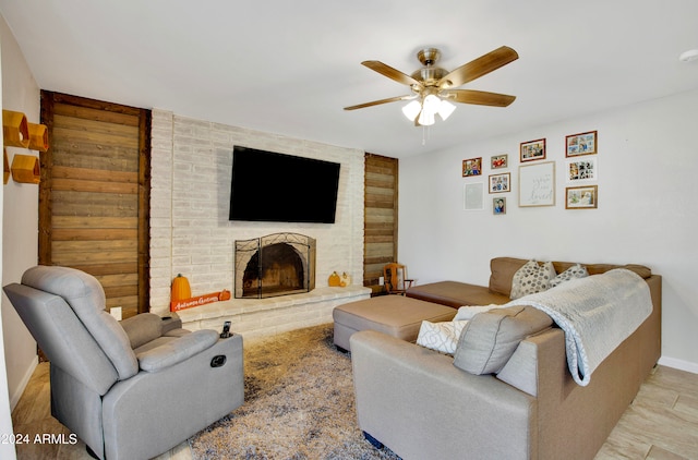 living room with light hardwood / wood-style flooring, ceiling fan, and a brick fireplace