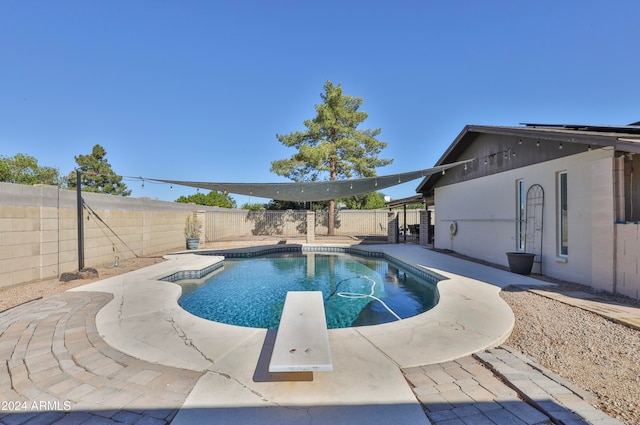 view of swimming pool with a diving board and a patio area