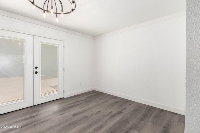 unfurnished room featuring an inviting chandelier, baseboards, french doors, and wood finished floors