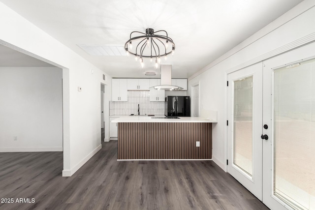 kitchen featuring white cabinets, light countertops, extractor fan, freestanding refrigerator, and a peninsula