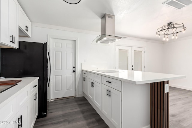 kitchen with a peninsula, light countertops, white cabinetry, island exhaust hood, and black appliances