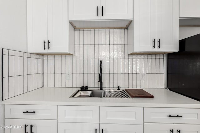 kitchen featuring light countertops, white cabinets, a sink, and tasteful backsplash