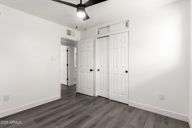 unfurnished bedroom with baseboards, visible vents, dark wood finished floors, and a closet