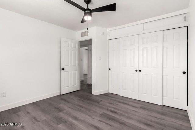 unfurnished bedroom with visible vents, a closet, wood finished floors, baseboards, and ceiling fan