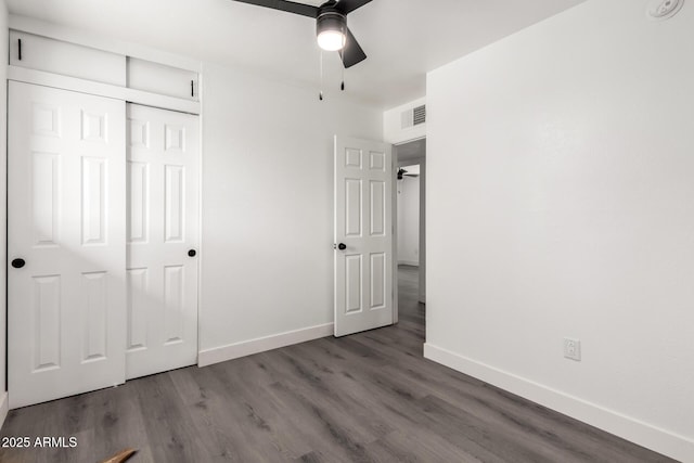 unfurnished bedroom featuring a ceiling fan, baseboards, wood finished floors, visible vents, and a closet