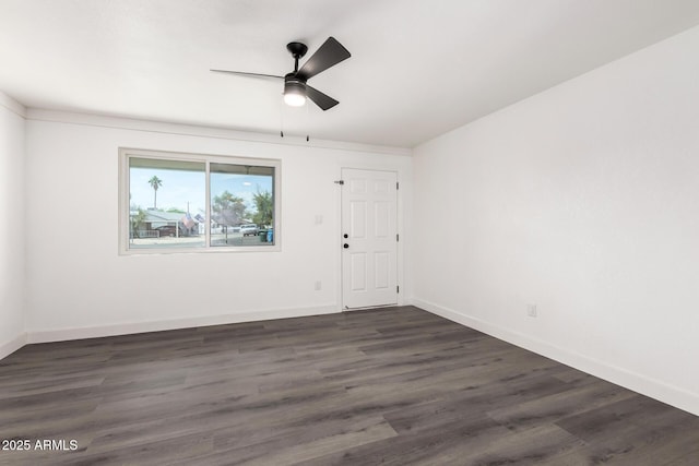 spare room with baseboards, a ceiling fan, and dark wood-style flooring