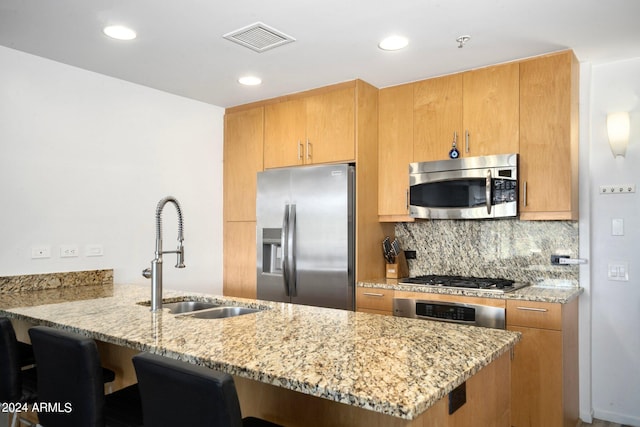 kitchen with light stone countertops, decorative backsplash, stainless steel appliances, sink, and kitchen peninsula