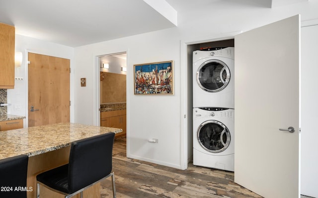 laundry room with stacked washer / dryer and dark hardwood / wood-style flooring