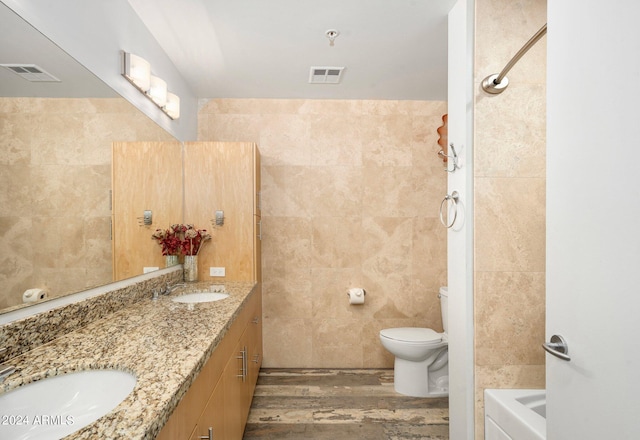 full bathroom with vanity, hardwood / wood-style flooring, plus walk in shower, tile walls, and toilet