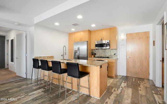 kitchen featuring light stone counters, sink, kitchen peninsula, dark wood-type flooring, and appliances with stainless steel finishes