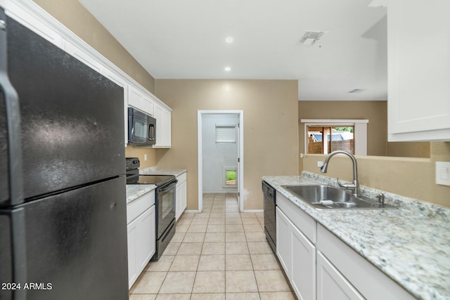 kitchen featuring light stone countertops, black appliances, light tile floors, sink, and white cabinetry