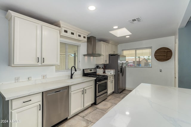 kitchen featuring light stone countertops, wall chimney exhaust hood, sink, and stainless steel appliances