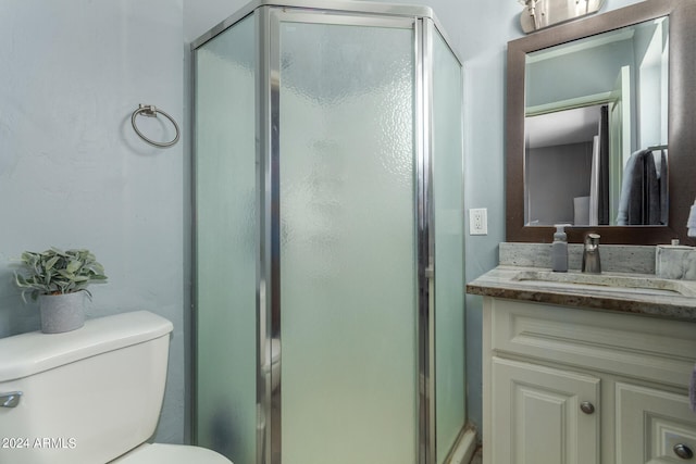 bathroom with vanity, a shower with shower door, and toilet