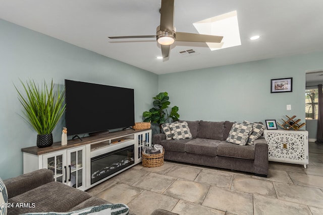 living room with ceiling fan and a skylight