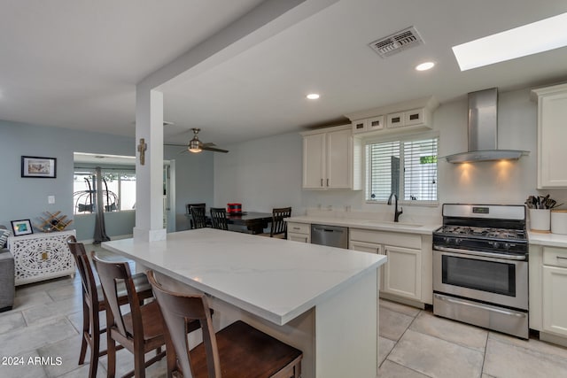 kitchen featuring sink, wall chimney range hood, stainless steel appliances, and a wealth of natural light