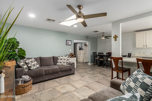 living room with ceiling fan and a skylight