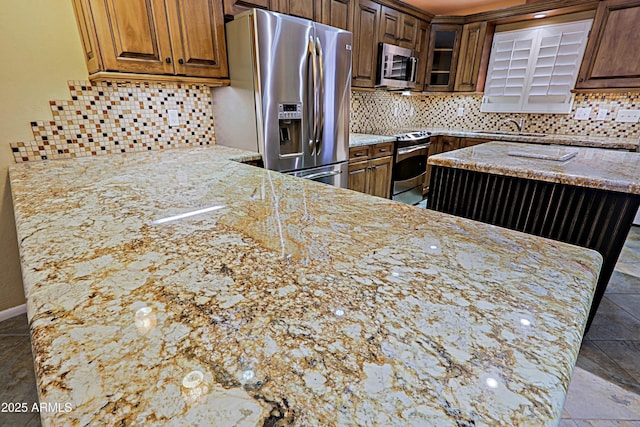 kitchen featuring appliances with stainless steel finishes, backsplash, and light stone counters