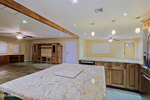 kitchen with a kitchen island, beam ceiling, light stone counters, and hanging light fixtures