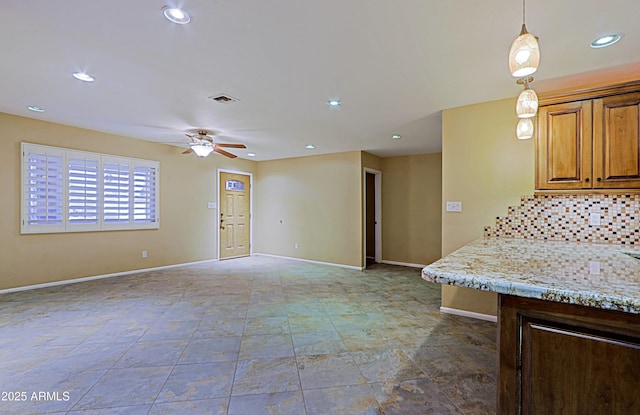 kitchen with ceiling fan, hanging light fixtures, light stone counters, and tasteful backsplash