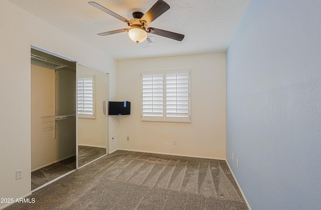 unfurnished bedroom featuring a textured ceiling, ceiling fan, a closet, and dark colored carpet