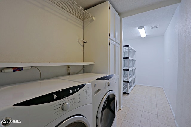 laundry area featuring a textured ceiling, cabinets, and washer and clothes dryer