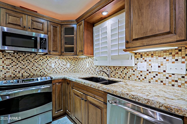 kitchen featuring sink, stainless steel appliances, backsplash, and light stone countertops