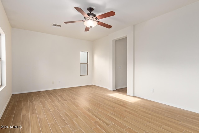 empty room featuring visible vents, ceiling fan, baseboards, and light wood-style floors