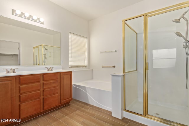 bathroom featuring wood finish floors, double vanity, a sink, a shower stall, and a bath