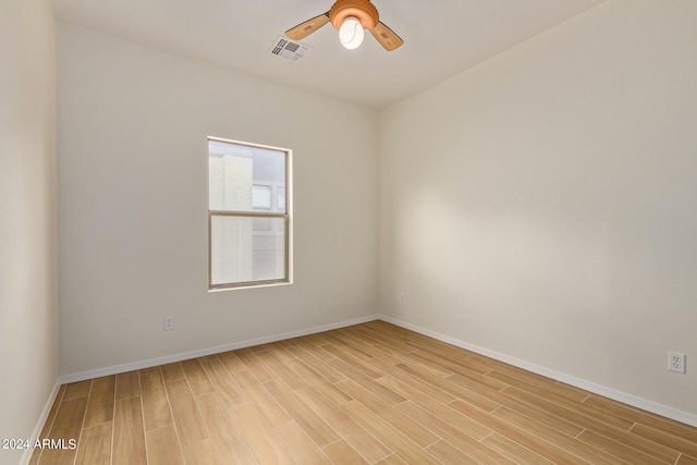 spare room featuring light wood finished floors, visible vents, baseboards, and ceiling fan