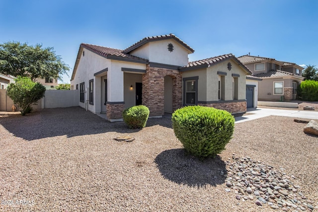 mediterranean / spanish-style house featuring stucco siding, driveway, a tile roof, stone siding, and an attached garage