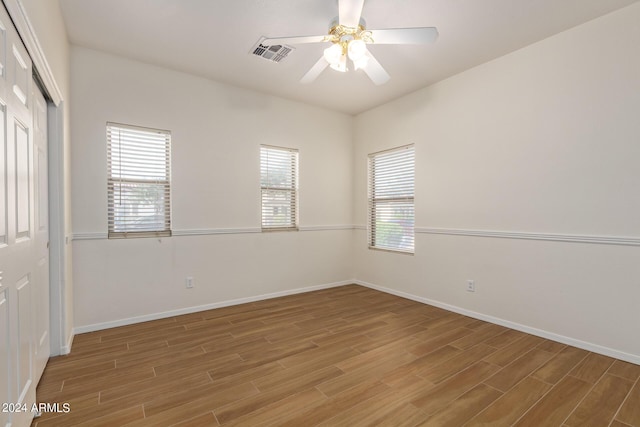 spare room with light wood-type flooring, visible vents, baseboards, and ceiling fan