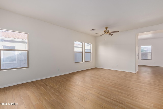 unfurnished room featuring light wood finished floors, visible vents, baseboards, and a ceiling fan