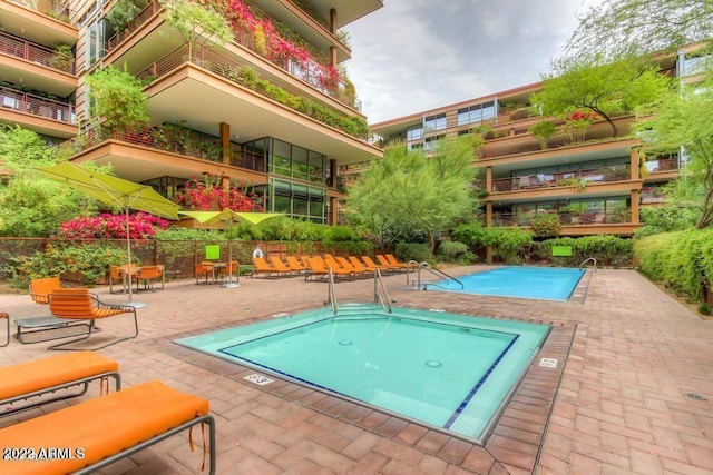 view of swimming pool featuring a community hot tub and a patio area