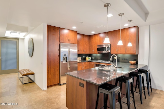 kitchen featuring a sink, brown cabinetry, stainless steel appliances, a peninsula, and decorative backsplash