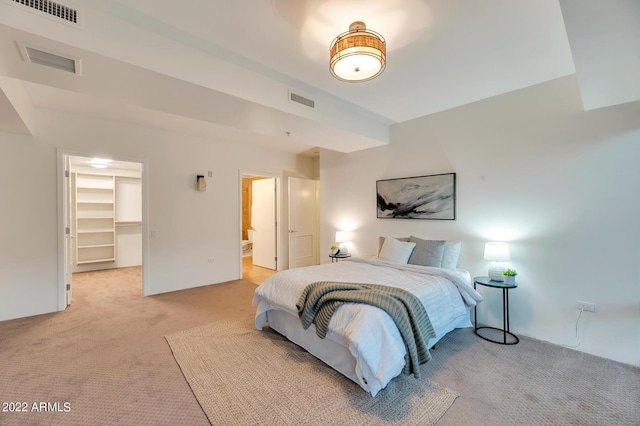 bedroom with a walk in closet, light carpet, and visible vents