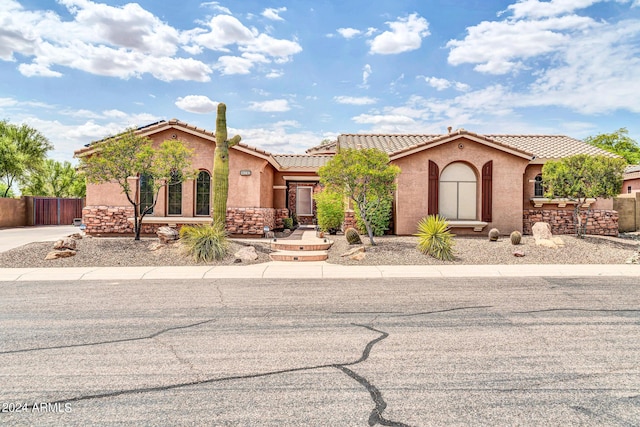 mediterranean / spanish-style home featuring a tiled roof, fence, and stucco siding