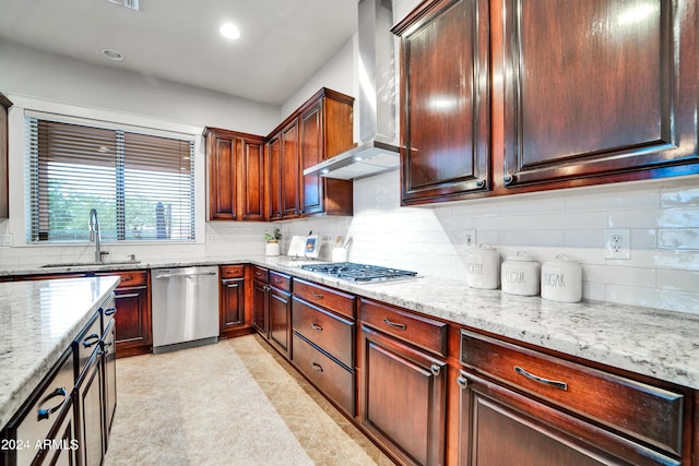 kitchen with wall chimney range hood, tasteful backsplash, stainless steel appliances, and a sink